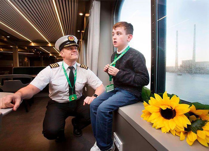 A boy is sitting on the edge of a window at the airport, and beside him, squatting in a squat, a pilot in command in uniform. Both have a sunflower string.